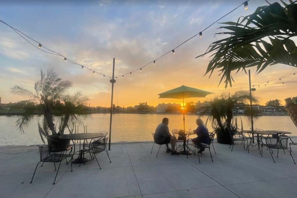 A couple sits at a table under an umbrella enjoying a dinner at sunset on the patio of the Kenosha Yacht Club.