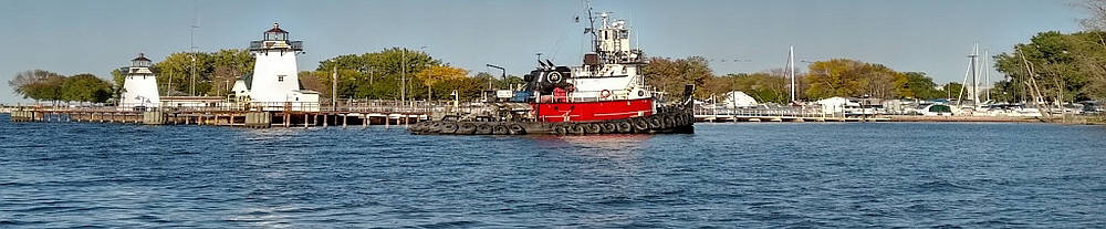 Harbor view near the Green Bay Yachting Club with two lighthouses on the left, and a red tug boat in the center.