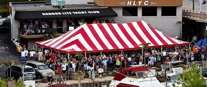 aerial view of a party under a big red and white tent in front of the Harbor Lite Yacht Club.