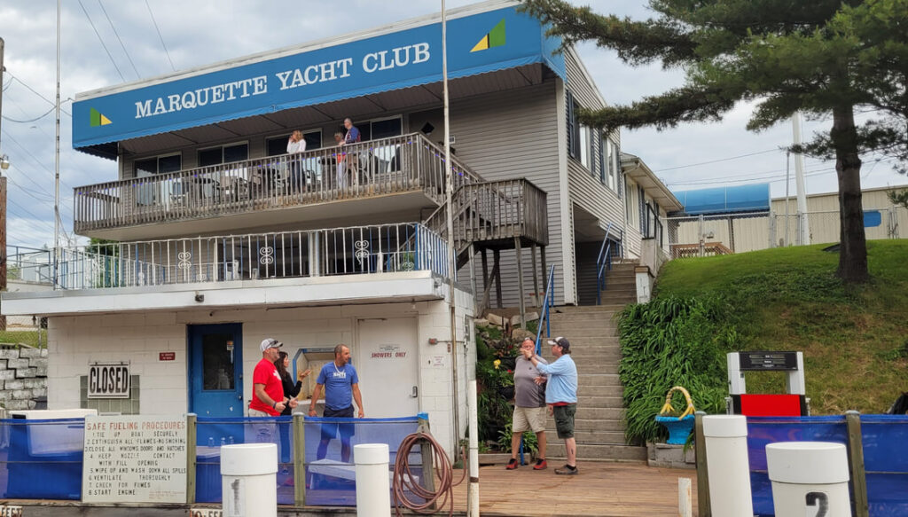 View of the back side of the Marquette Yacht Club deck with several boaters standing around.