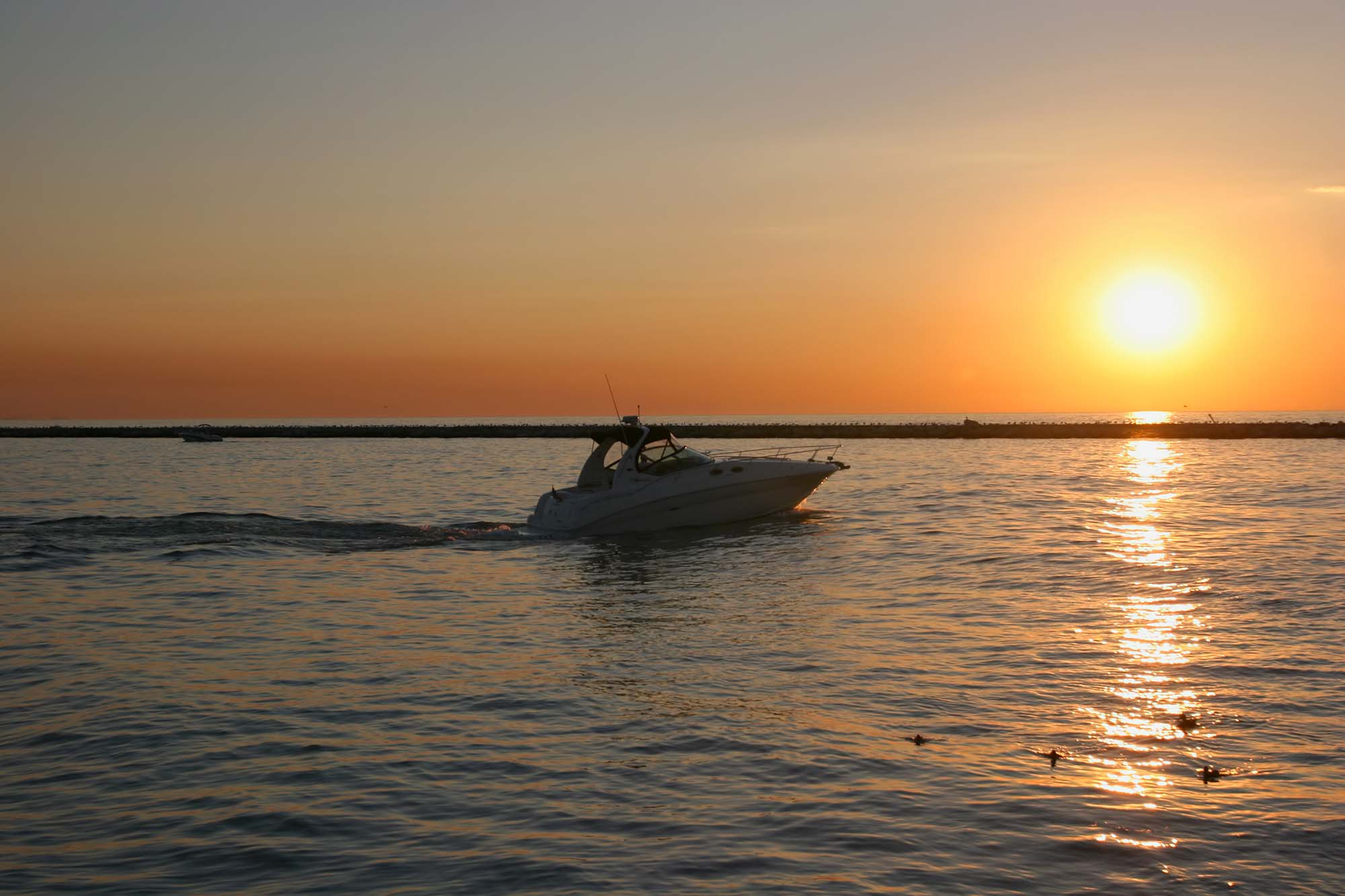 A boat is cruising in Lake Michigan with the sunset in the background