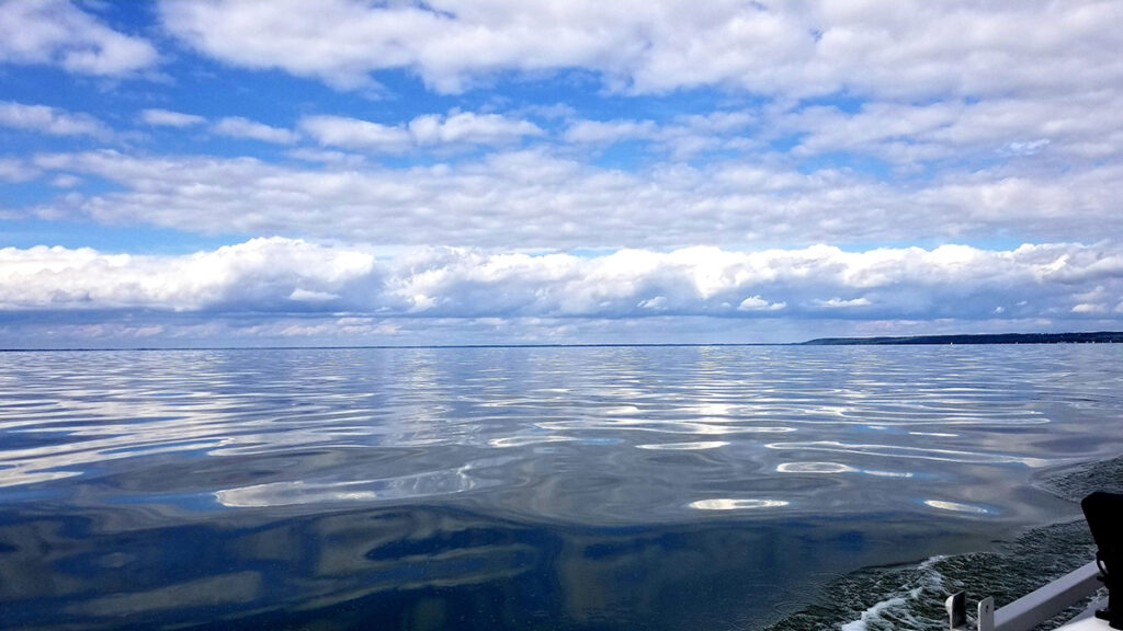 Beautiful view of the shiny, calm waters of and blue skies with cloud banks above Lake Winnebago near Oshkosh, Wisconsin.