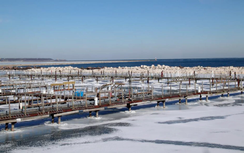 South Shore Yacht Club harbor with breakwater construction in progress, showing lots of rocks being piled up in the water, not yet evenly finished.